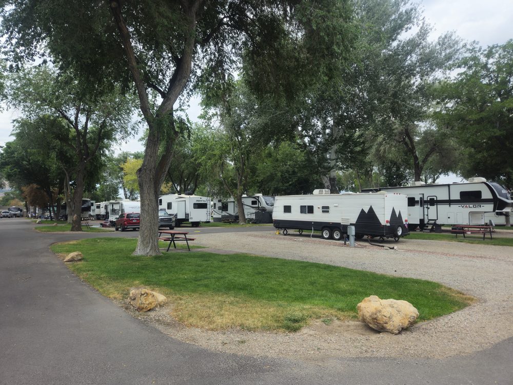 Long-term RV site with travel trailer, green space and mature trees